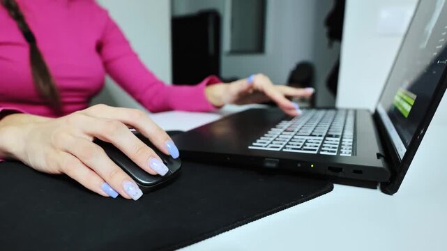 Wide close up of woman in pink sweater editing social content at home desk