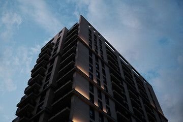 Obraz premium Close-up of a modern apartment building with glowing lights at dusk in Belgrade Waterfront, Serbia.