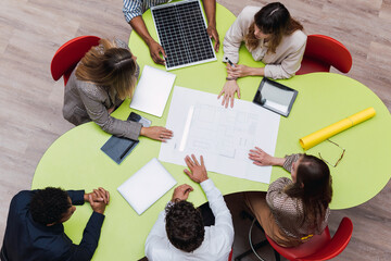 High angle view of business colleagues having a meeting with plan, wireless devices and solar panel on table