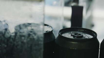 Chilled black aluminum beverage cans resting in crystalline ice water, condensation forming, capturing refreshing summer coolness with sparkling droplets and enticing beverage presentation