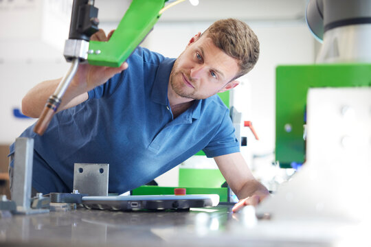 Engineer analyzing machine part in factory