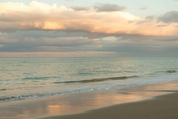 Obraz premium Gentle waves on sandy shore at sunset beach ocean