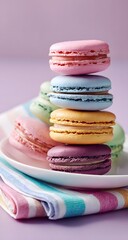Fototapeta premium Colorful pastel macarons stacked on a plate with striped fabric background