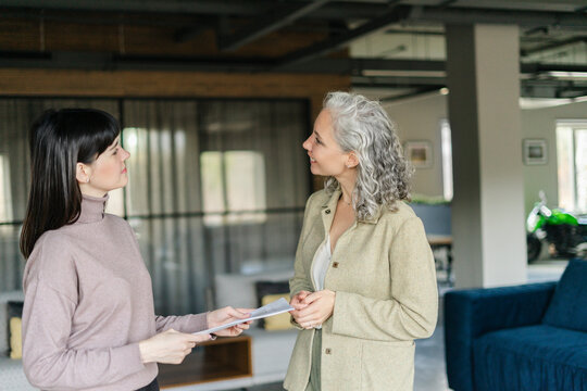 Two women with document in office facing each other