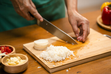 Hands slicing Radish on a wooden board in the kitchen, preparing to cook.