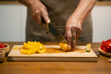 hands cutting bell peppers in the kitchen.