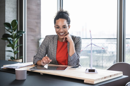 Happy businesswoman with hand on chin at work place