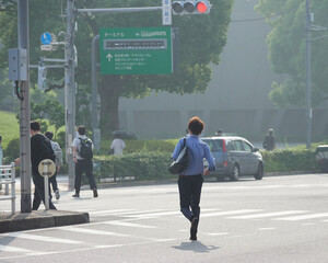 夏の朝の都市の街の横断歩道を渡る通勤中の人たちの姿