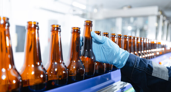 Automated beer bottling process in modern brewery environment. Worker quality control on food industry