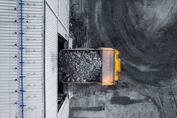 Open pit mine, big mining truck unloads gold ore for crusher, aerial top view