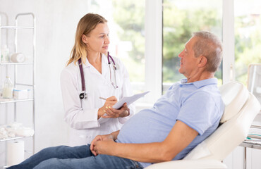 Adult woman medic makes notes in documents in medical room