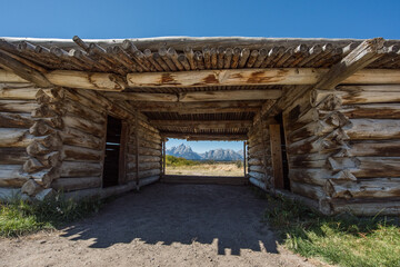 A log cabin with a view of the Teton mountains.