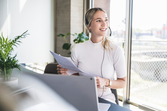 Smiling customer service representative sitting with document in office