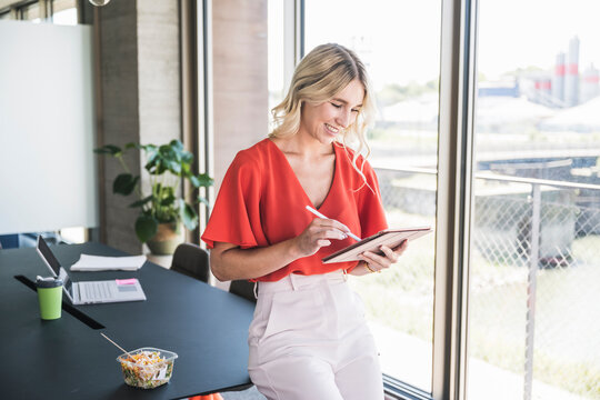 Smiling businesswoman using tablet PC with digitized pen in office