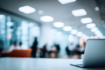 Laptop on desk in modern office with blurred coworkers
