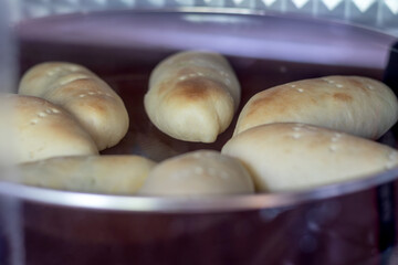 Bread rolls baking to golden perfection inside an electric oven. Dough is rising and browning, showcasing process of home baking