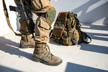 Soldier Equipment: Close-up of soldier's equipment, showcasing a sturdy boot, advanced rifle, and tactical backpack, symbolizing preparedness and duty.