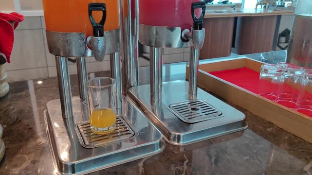 juice being poured from a dispenser into a glass during a hotel breakfast buffet. This clip captures a typical morning dining experience, highlighting the convenience and freshness