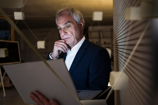 Digital composite image of thoughtful businessman with laptop in office