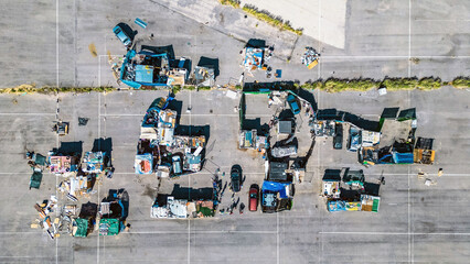 Aerial view of makeshift shelters and scattered debris paint a stark picture on the cracked asphalt, a harsh reality under the vast sky., Valencia, Valencian Community, Spain.