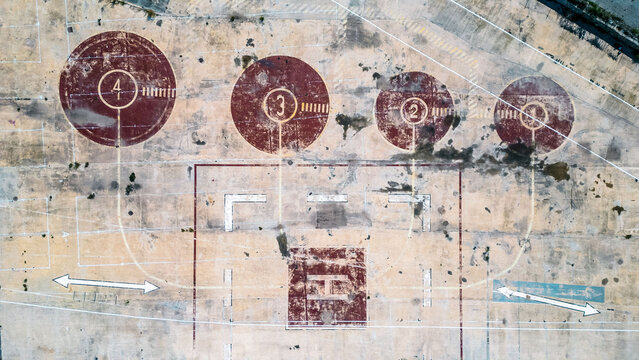 Aerial view of faded, weathered helipad markings and numbered target zones create a stark, textured landscape of decaying infrastructure., Valencia, Valencian Community, Spain.