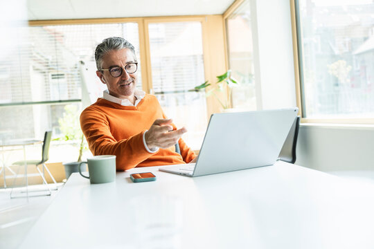 Mature businessman talking on video call through laptop in office