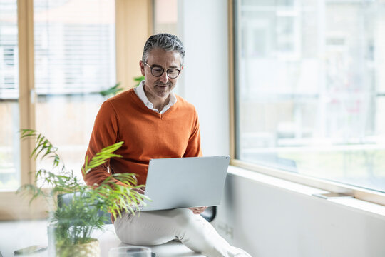 Businessman working with laptop sitting on table at office