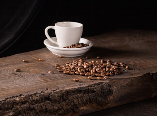 Artistic low key photography of a white coffee cup with coffee beans