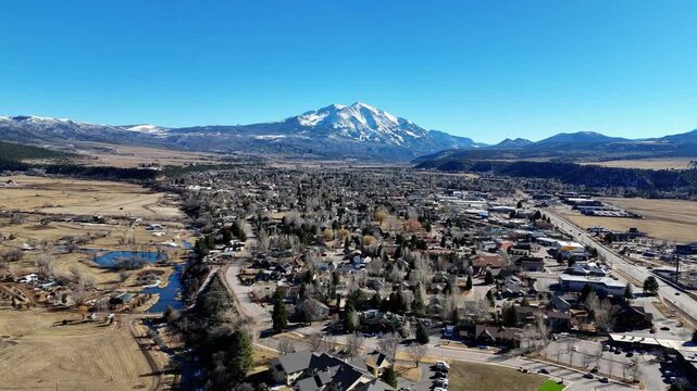 Aerial view of Carbondale, Colorado, nestled beneath the snow-capped Mount Sopris, a scene of earthy browns contrasting with the crisp blue sky, Carbondale, Colorado, United States.