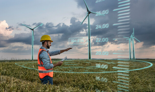 Engineer wearing hardhat and programming digital wind turbine through tablet PC in field