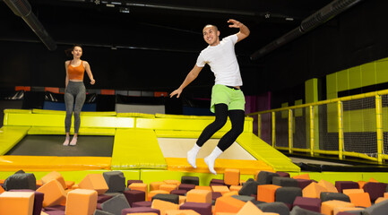 Happy excited young man playfully diving into colorful foam cube pit at lively indoor trampoline park