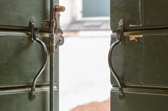Through the opened old window blinds, wooden green doors
