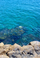 Tranquil blue transparent clean ocean water and rocks nature background.Water washing on shoreline  on bright sunny day. Summer,vacation, beach, travel, relax concept.
