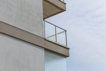 Balcon moderne sur un bâtiment urbain sous un ciel nuageux en milieu d'après-midi.