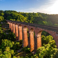 A long red brick arch bridge through lush green hills