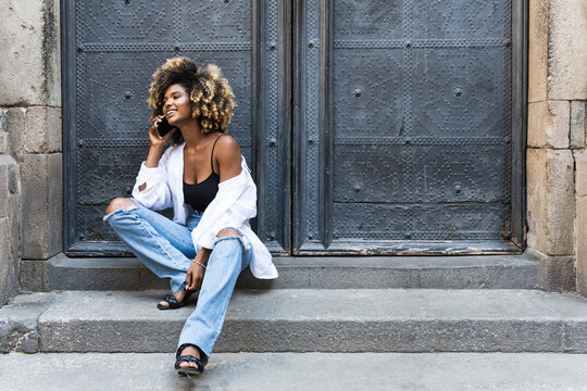 Smiling latin woman talking very happy on cell phone with friends rejoicing laughing white teeth. Young African American girl call to her family abroad on mobile phone