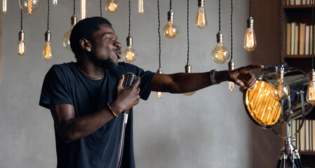 Professional jazz singer African american man sings song holding retro microphone in hands on stage