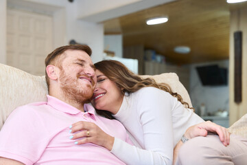 Happy couple relaxing and embracing on sofa at home