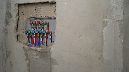 Water pipes and valves emerging from concrete wall during plumbing installation