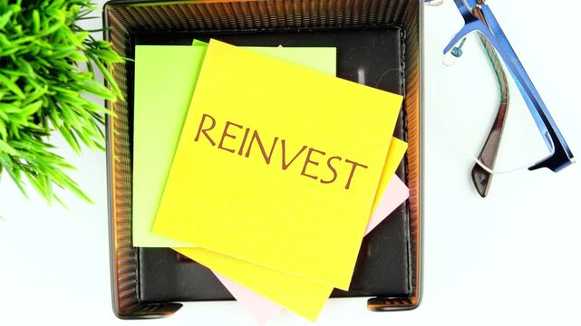 The phrase REINVEST appears on a yellow sticker. Animation of the word REINVEST. Business concept.