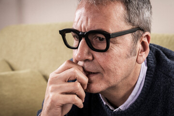 Close-up of an anxious mature man biting his nails, showing stress and worry. Concept of mental health problems, anxiety disorder and bad habits.