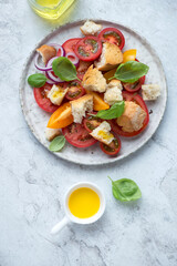 Plate with italian panzanella salad on a white stone background, vertical shot, above view