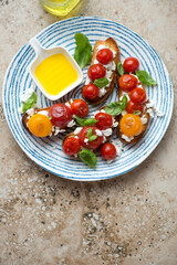 Blue and white plate with roasted tomato and ricotta bruschettas, vertical shot on a beige granite background with space, flat lay