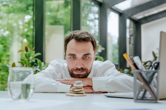Businessman looking at stack of pebble stones in office