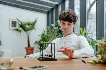 Smiling businessman playing with newton's cradle in office