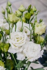 beautiful floral arrangement featuring white roses and delicate green buds set against neutral backdrop, showcasing serene beauty nature in full bloom. vertical. close up.