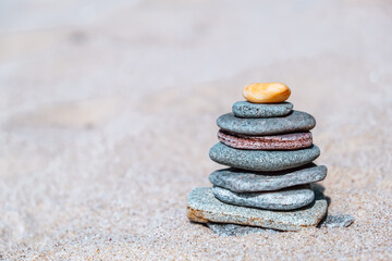 carefully arranged stack smooth stones rests on warm sand, glistening under sunlight. natural colors stones enhance serene beach atmosphere. close up.