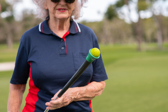 senior woman with putter and golf ball