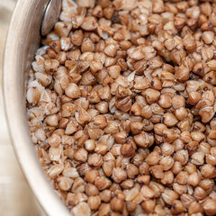 Plate with tasty buckwheat porridg.Boiled buckwheat porridge in ceramic pot on wooden background.