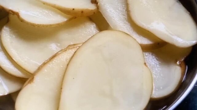 thinly sliced raw potatoes, which are indeed likely being prepared for making potato chips or crisps, as well as a bowl containing a batter of gram flour, possibly for coating these potato slices
